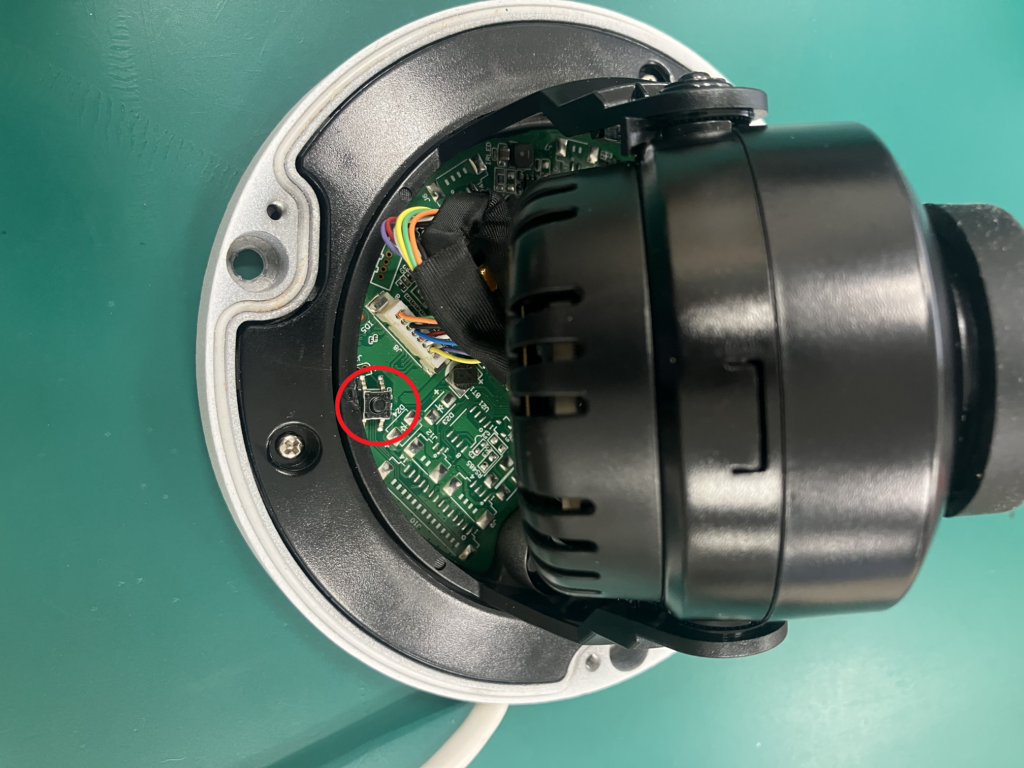 写真は:Dahuaのドーム型ネットワークカメラをファクトリーリセットするためのボタンの位置を図示しています。付属のスパナでドームカバーを外し、基板上のボタンを押下する必要があります