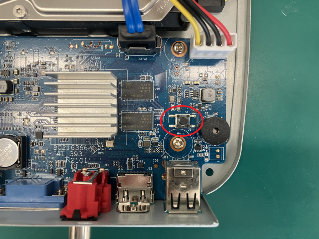 写真は:Dahuaのレコーダーをファクトリーリセットするためのボタンの位置を図示しています。フロントパネルを外し基板上のボタンを押下する必要があります。